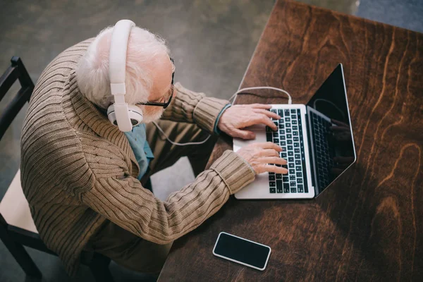 Blick von oben auf einen älteren Mann mit Kopfhörer und Laptop — Stockfoto