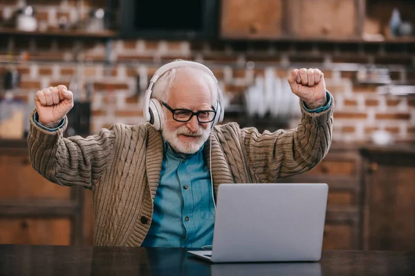 Älterer Mann mit Kopfhörer und Laptop aufgeregt — Stockfoto
