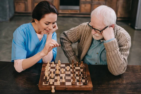 Vue du dessus de l'infirmière et du vieil homme jouant aux échecs — Photo de stock