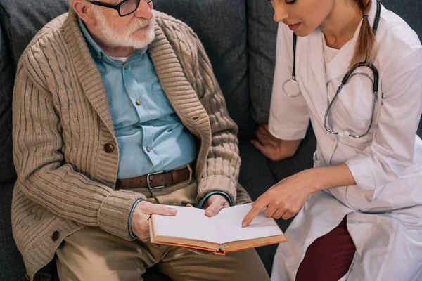 Vieil homme patient et médecin discutant intrigue du livre — Photo de stock