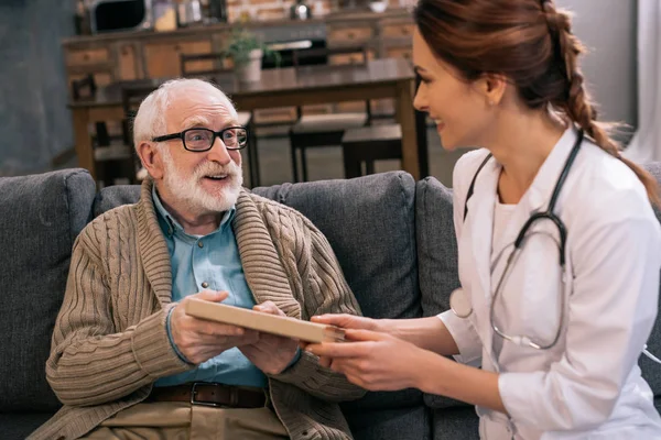 Doutor apresentando livro para homem sênior — Fotografia de Stock