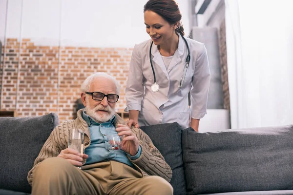 Médecin debout par un homme âgé prenant des médicaments — Photo de stock