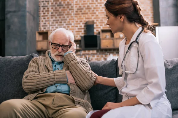 Женщина-врач поддерживает грустного пожилого мужчину — стоковое фото