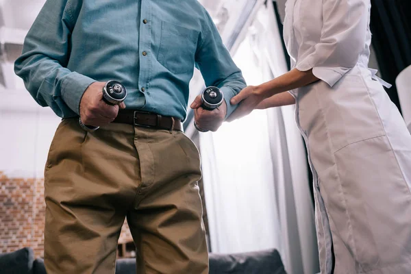 Close-up view of doctor instructing senior man exercising with dumbbells — Stock Photo