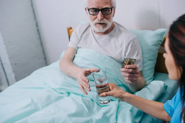 Krankenschwester gibt Patientin mit Tabletten ein Glas Wasser — Stockfoto