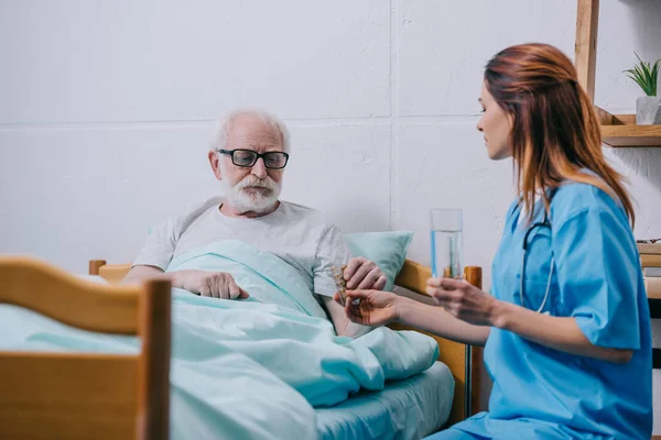 Infirmière donnant un verre d'eau au patient avec des pilules — Photo de stock