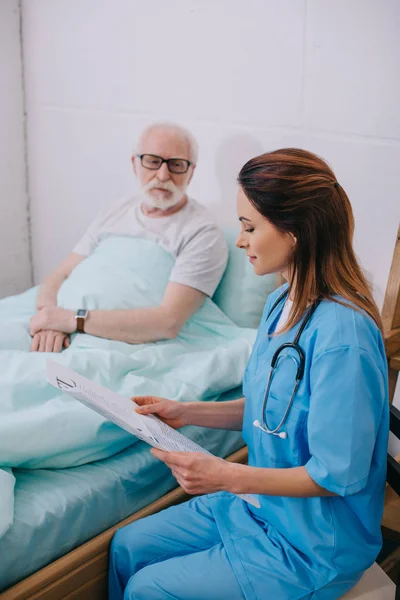 Enfermeira explicando conselhos médicos para o paciente idoso na cama — Fotografia de Stock