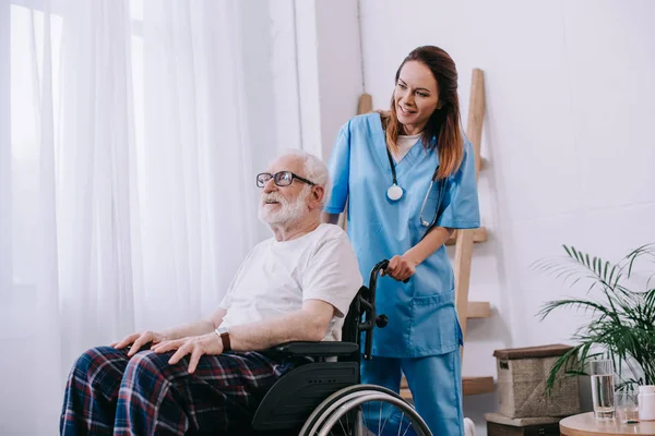 Krankenschwester schubst Rollstuhl mit Senioren — Stockfoto