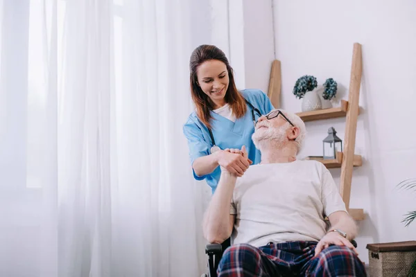 Infermiera sostenere e tenere la mano di sorridente anziano paziente uomo — Foto stock