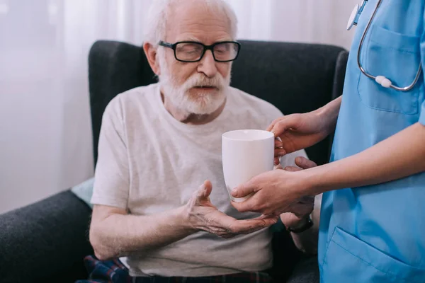 Nurse giving cup with drink to senior patient — Stock Photo