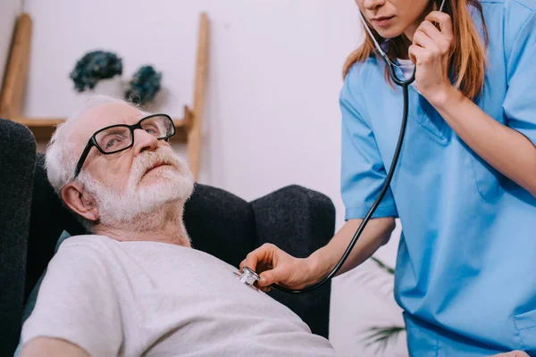 Krankenschwester mit Stethoskop überprüft Herzschlag kranker Seniorin — Stockfoto