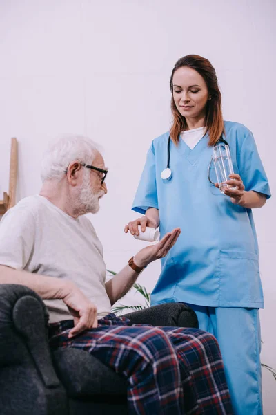 Female nurse giving pills to senior patient — Stock Photo