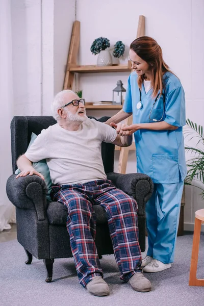Pflegerin hält lächelnde Seniorin an der Hand — Stockfoto