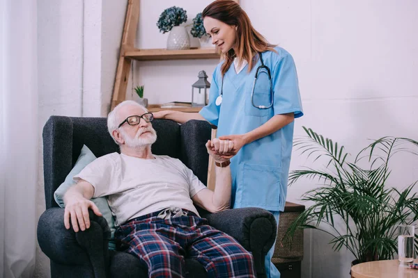 Caregiver supporting and holding hand of tired senior man — Stock Photo