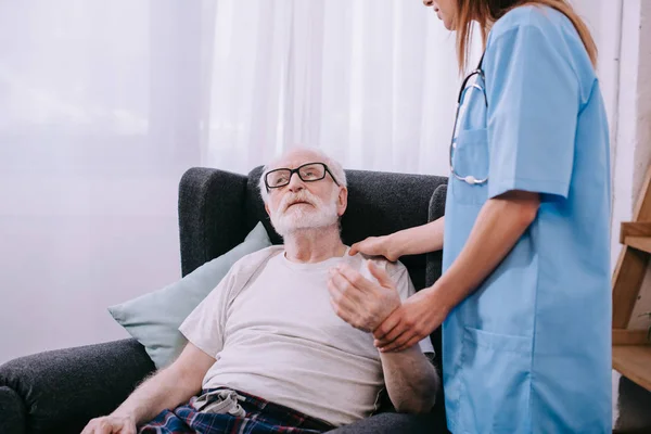 Nurse checking heartbeat of senior man — Stock Photo