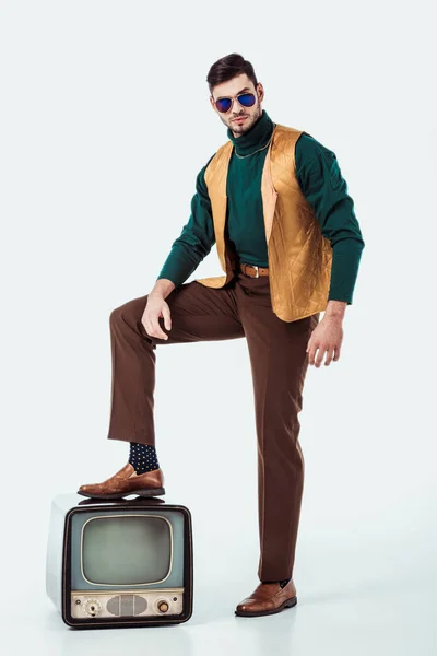 Schöner Mann im Retro-Stil, der Bein auf Vintage-Fernseher auf weiß setzt — Stockfoto