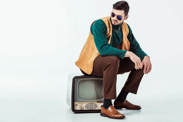 Handsome retro styled man sitting on vintage television on white — Stock Photo