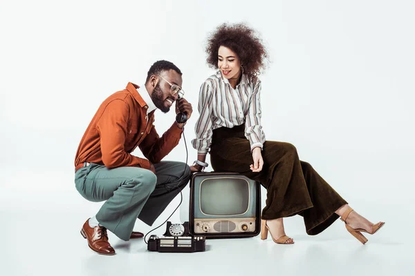 African american retro styled couple with vintage television and phone on white — Stock Photo