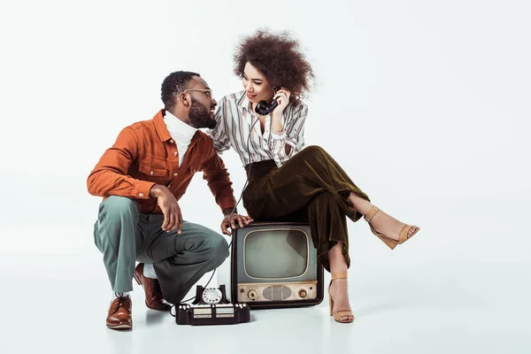 Afroamericana retro styled novia sentado en vintage televisión y y hablando por teléfono en blanco - foto de stock