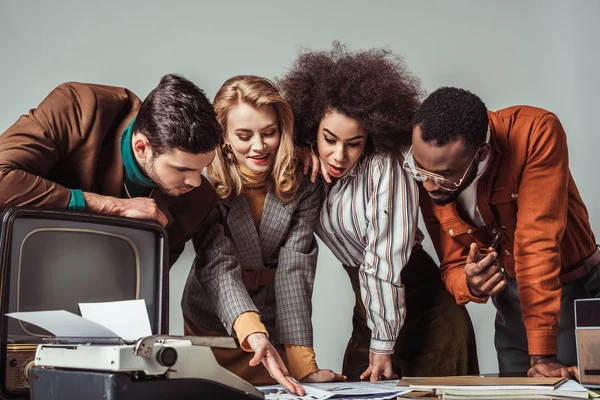 Periodistas multiétnicos de estilo retro leyendo periódicos aislados en gris - foto de stock