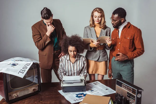 Periodistas multiculturales de estilo retro en la sala de redacción en gris - foto de stock