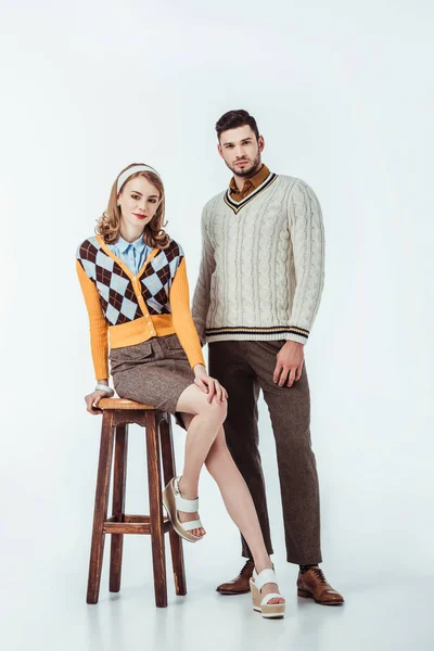 Beautiful retro styled couple with wooden chair looking at camera on white — Stock Photo