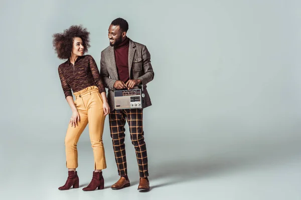 Feliz Africano americano retro estilo casal olhando um para o outro com rádio vintage em cinza — Fotografia de Stock