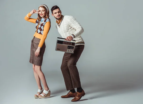 Beautiful retro styled couple dancing with vintage radio on grey — Stock Photo