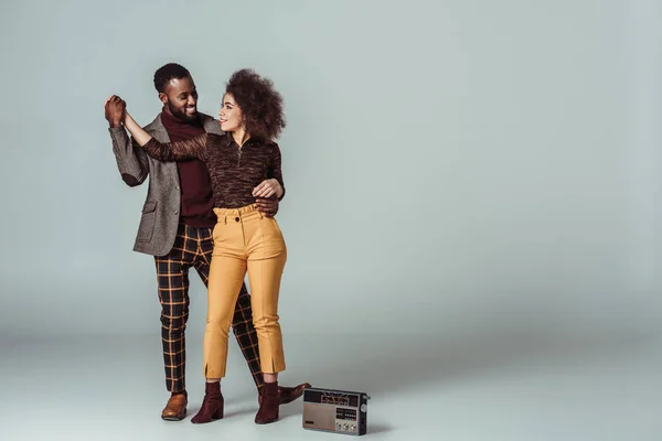 African american retro styled couple dancing on grey, vintage radio on floor — Stock Photo