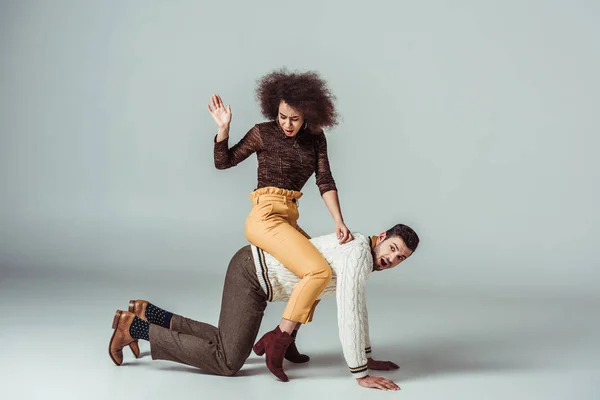 African american retro styled girl sitting on boyfriends back and having fun — Stock Photo