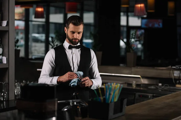 Schöner Barkeeper, der abends Glas mit Lappen reinigt — Stockfoto