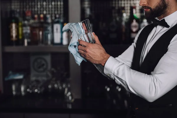 Cropped image of bartender cleaning glass with rag in evening — Stock Photo