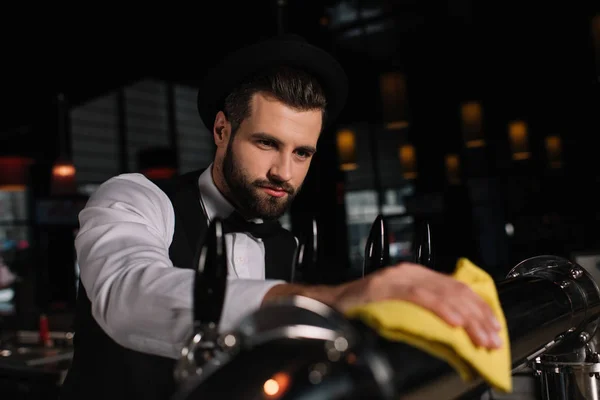 Handsome bartender cleaning beer taps with rag — Stock Photo