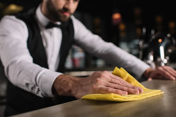 Cropped image of bartender cleaning bar counter in evening — Stock Photo