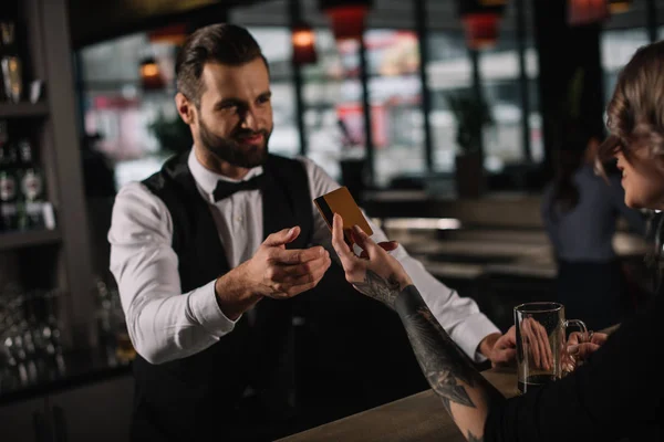 Visitante dando cartão de crédito ao barman para pagar por bebidas — Fotografia de Stock