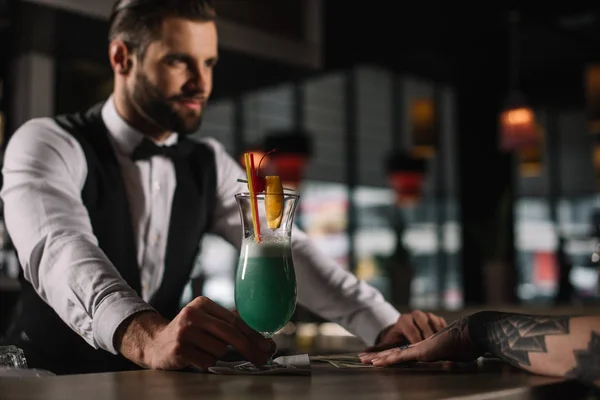 Beau barman donnant boisson alcoolisée à la fille au comptoir du bar — Photo de stock