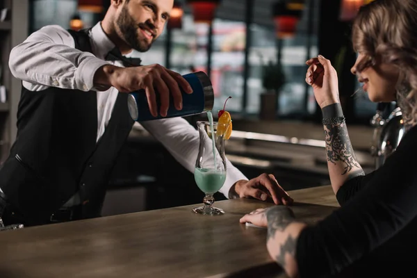 Lächelnd schöner Barkeeper bereitet Alkohol-Cocktail für Mädchen vor — Stockfoto