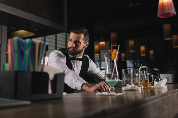 Bonito barman inclinado no bar balcão e olhando para longe — Fotografia de Stock