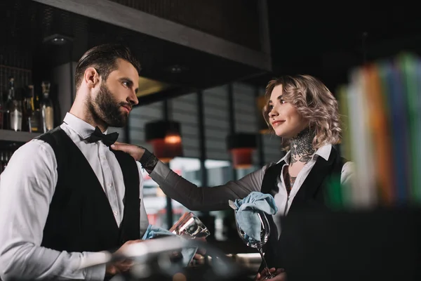 Bartenders cleaning glasses and looking at each other at bar — Stock Photo