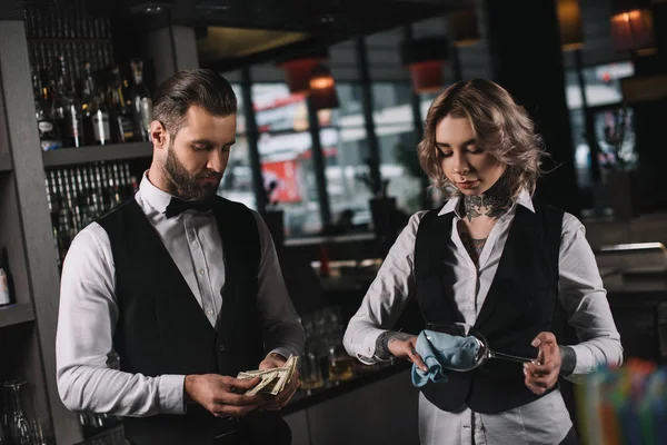 Bartenders counting tips and cleaning glasses at bar — Stock Photo