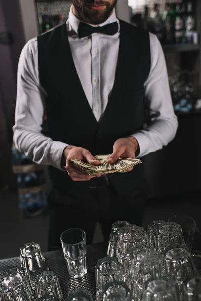 Cropped image of bartender counting tips at bar counter — Stock Photo