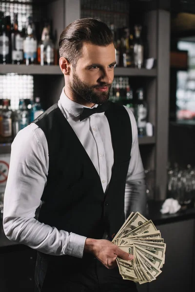 Happy handsome bartender holding tips at bar — Stock Photo