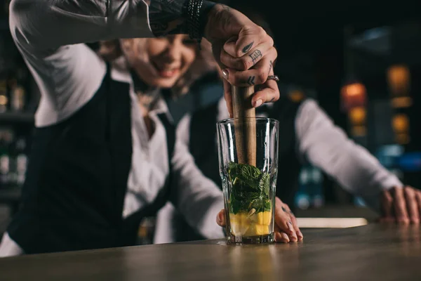 Femme barman tatouée montrant à son collègue comment préparer une boisson au bar — Photo de stock