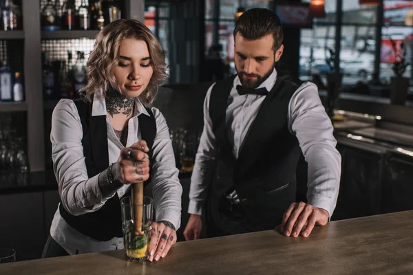 Barman feminino mostrando colega como preparar bebida no bar — Fotografia de Stock