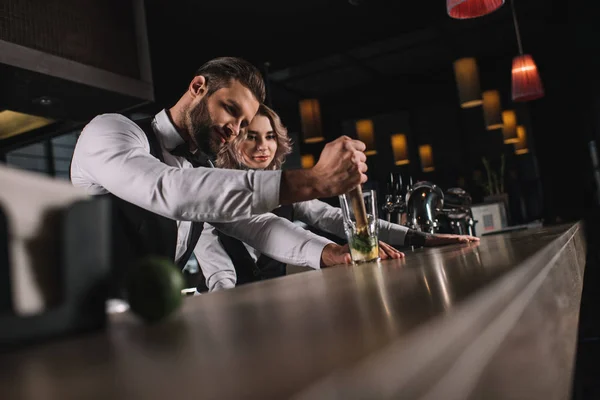 Camarero masculino mostrando colega cómo preparar bebida en el bar - foto de stock