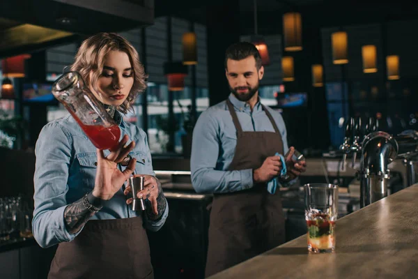 Cantineros femeninos y masculinos que trabajan en el bar - foto de stock