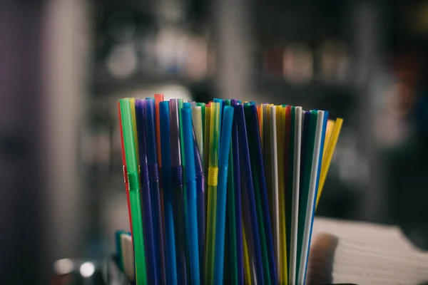 Palhas de plástico coloridas para beber em fundo desfocado — Fotografia de Stock