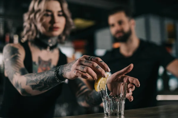 Bartender putting piece of lemon in glass at bar — Stock Photo