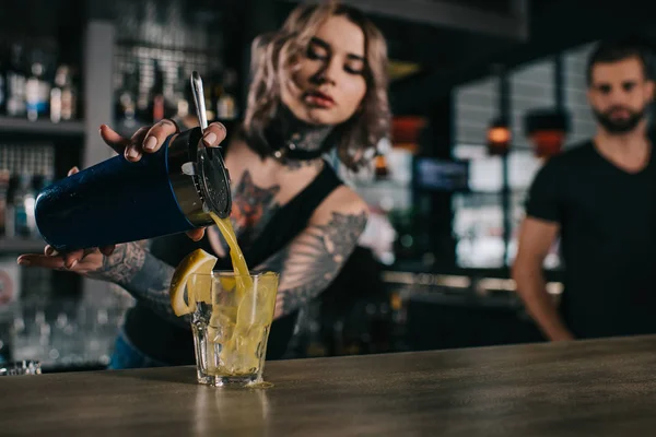 Tattooed bartender preparing drink at bar — Stock Photo