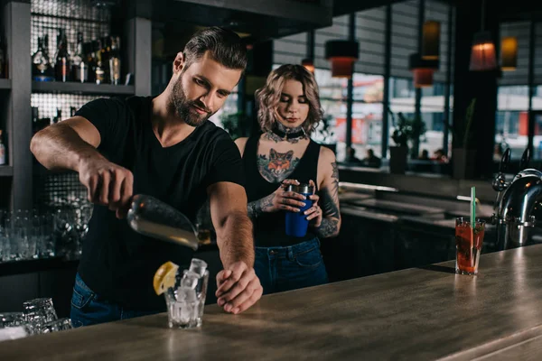 Jeunes barmans préparant des boissons alcoolisées au comptoir du bar — Photo de stock